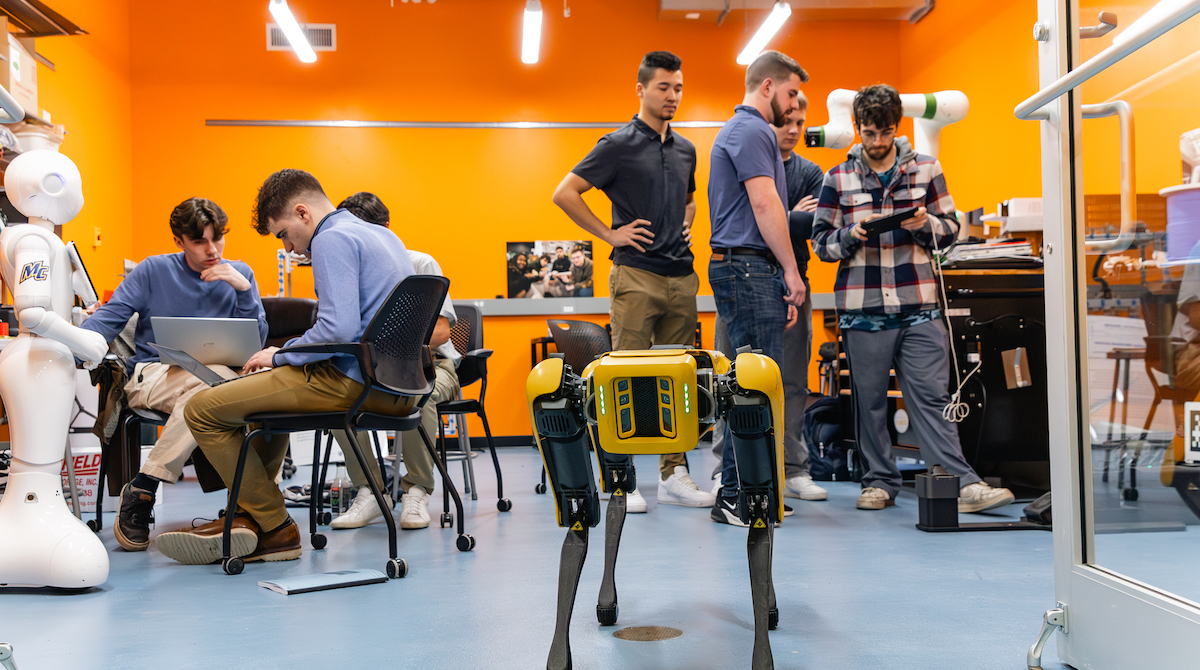 Visitors exploring a robotics lab with a collaborative robot